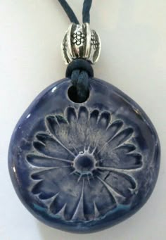 a blue pendant with a flower design on it's side and a black cord