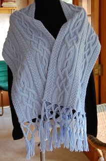 a white knitted shawl with tassels on it