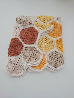 a crocheted dishcloth is shown on a white surface with oranges and browns