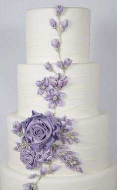 a three tiered cake with purple flowers on it