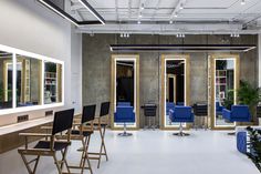 a salon with blue chairs and mirrors in front of the doors that have lights on them