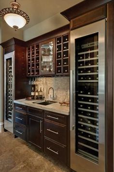 a wine cellar in the middle of a kitchen with dark wood cabinets and marble counter tops