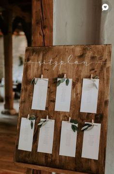 a wooden sign with notes attached to it and greenery on the back of it