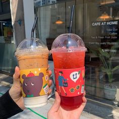 two people holding up cups with drinks in them