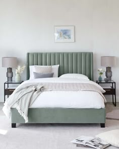 a bedroom with a bed, nightstands and pictures on the wall above it in white