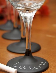 three wine glasses sitting on top of black coasters with writing on the bottom one