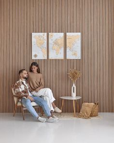 two people are sitting on a chair in front of a wall with striped walls and wooden paneling