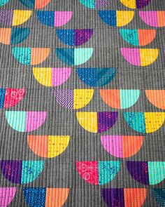 a colorful quilt is displayed on a table top with an orange, yellow and blue design