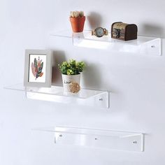 two white shelves with plants and pictures on them