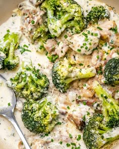 a bowl filled with broccoli and chicken covered in white sauce next to a spoon