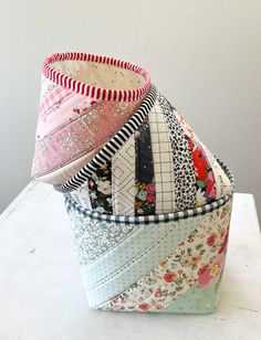 several different types of fabric stacked on top of each other in a basket with white walls behind them