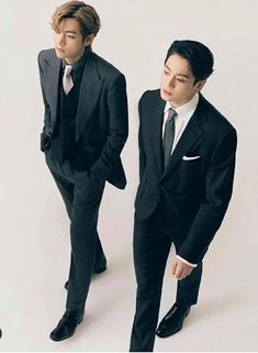 two young men in suits and ties standing next to each other, one wearing a suit