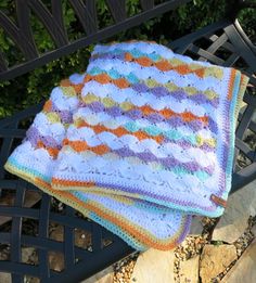 two crocheted blankets sitting on top of a bench