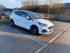 a white car parked in a parking lot next to another car on the other side