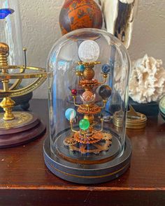 a glass dome with various items under it on a wooden table next to other objects