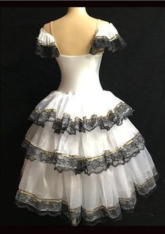 a white dress with black lace on the bottom and gold trim around the bustle