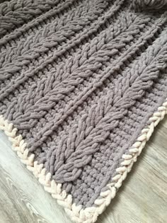 a crocheted blanket is laying on the floor next to a wooden floor with wood floors