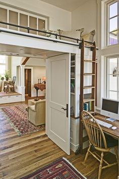 a room with a loft bed, desk and chair next to a large open door