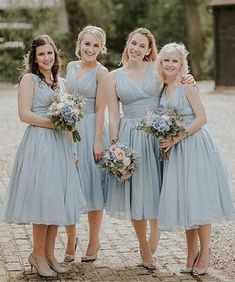 four bridesmaids in blue dresses posing for a photo on a cobblestone walkway