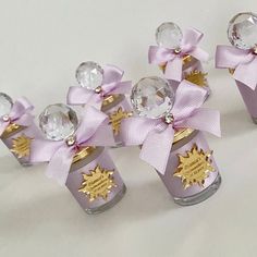 four small glass vases with bows and jewels in them on a white table top