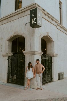 a man and woman standing next to each other in front of a building