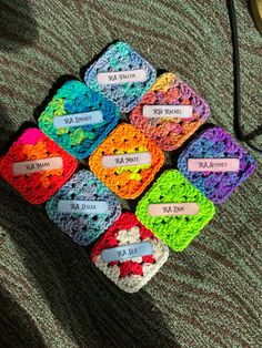 The image depicts 9 crocheted granny squares arranged in a diamond shape. The squares are made out of acrylic yarn in different colors. On each square, there is a rectangle piece of cardstock paper with a name on it. Hall Themes, Resident Assistant Door Decs, Res Life, Door Decs, Resident Assistant