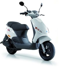 a white scooter is parked on a white surface with black wheels and spokes