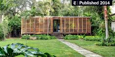 a wooden structure sitting in the middle of a lush green field with lots of trees