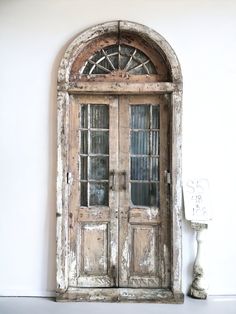 an old wooden door with two glass panes on the top and bottom, in front of a white wall