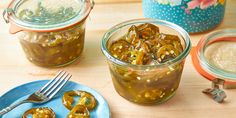 pickled jalapenos sit in glass jars on a table next to plates