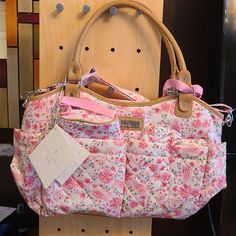 a pink floral purse sitting on top of a wooden stand