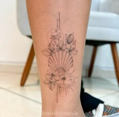 a woman's leg with a flower and fan tattoo on her left side calf