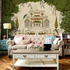 a living room with a couch, coffee table and bookcase in front of a wall mural