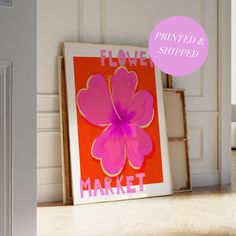 a pink flower is displayed in front of an orange and pink poster on the floor