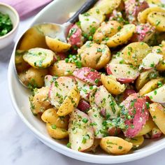 a white bowl filled with potatoes and parsley