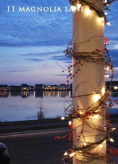 a pole covered in lights next to a body of water at night with the words 1 magnolia lane written on it