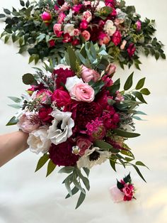 two bouquets of flowers are being held by someone's hand on a white surface