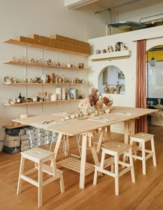 a wooden table and chairs in a room with shelves on the wall behind it,