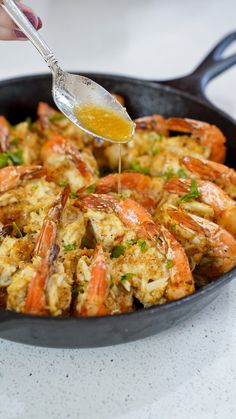 a pan filled with cooked shrimp being drizzled with sauce