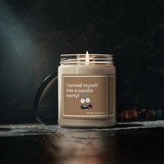 a candle sitting on top of a wooden table next to a cup filled with liquid