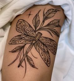 a woman's thigh with a dragonfly tattoo on it