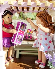 two dolls are playing with each other in the doll house and one is holding a box