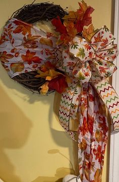 a wreath with fall leaves hanging on the wall next to a cup and coffee mug