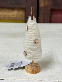 a small white christmas tree with gold stars on it's top sitting on a wooden stand