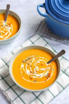 two bowls of carrot soup on a table