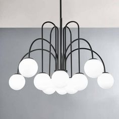 a modern chandelier with white balls hanging from it's black metal frame