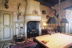 a pool table in front of a fireplace with deer heads on the wall behind it