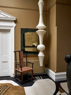 a room with a chair, lamp and paintings on the wall