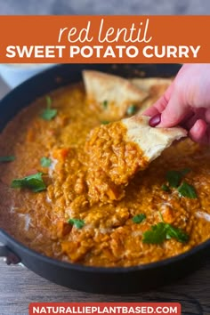 a hand dipping tortilla chips into a bowl of red lentil sweet potato curry