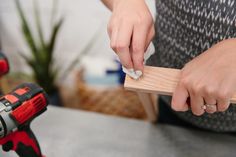 a woman is using a screwdriver on a piece of wood